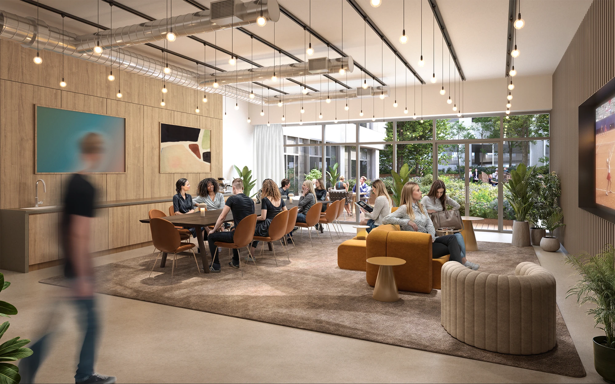 Office social lounge with warm lighting, modern decor, and employees chatting around a shared table